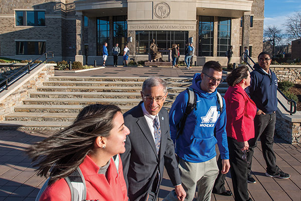 Assumption President Francesco C. Cesareo, Ph.D., walks with students in front of the new Tsotsis Family Academic Center.
