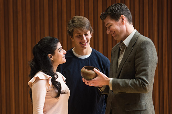 Associate Professor Mark Christensen, Ph.D.,  shows a burnished clay bowl from Colima, Mexico, estimated to be from around 300 B.C. – 350 A.D., to students 
Joseph Baron ’19 and Remie El-Hayek ’18.