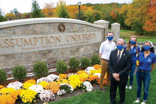 President Francesco C. Cesareo, Ph.D., stands in front of the new Assumption University sign at the entrance of the Worcester Campus with students (FROM L TO R) Eli Beberman ‘22, Christina Kuss ‘21, and Hannah White ‘21.