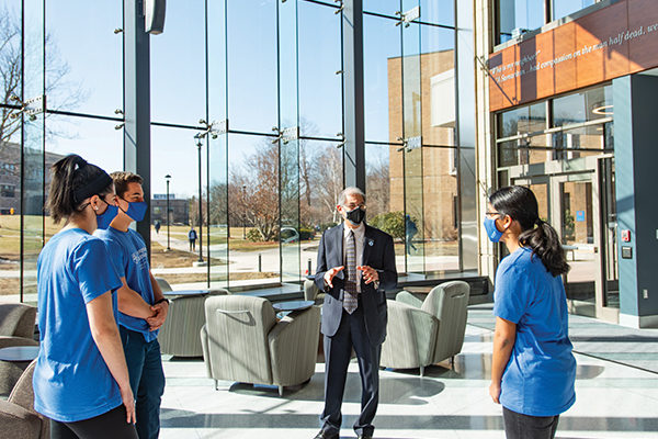 Assumption University President Francesco C. Cesareo, Ph.D., talks with students in the lobby of the new Health Sciences Building.