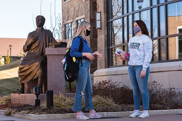 A statue of St. Augustine welcomes students like Lily O'Conor ’21 and Taylor Poland ’22 as they enter the Tsotsis Family Academic Center, a reminder of their pursuit of knowledge and a Catholic liberal education.